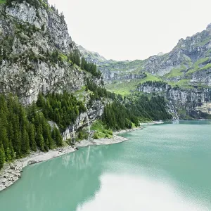 Calm lake encircled by cliffs and greenery with overcast skies