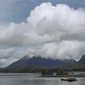 Calm lake waters with mountain backdrop and clouds in a blue sky in Tofino Calm lake waters with mountain backdrop and clouds in a blue sky in Tofino