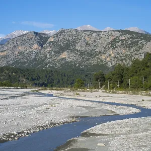 A calm river flows through a wide gravel bed