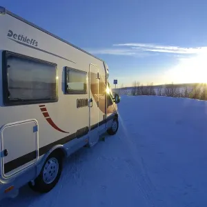Camper driving through wintry landscape at sunset Camper driving through wintry landscape at sunset