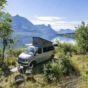 Camper standing by fjord with view of mountains