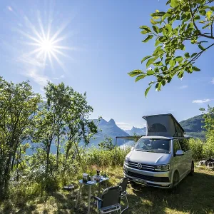 Camper standing by fjord with view of mountains Camper standing by fjord with view of mountains