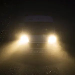 Campervan with bright lights standing in the fog Campervan with bright lights standing in the fog