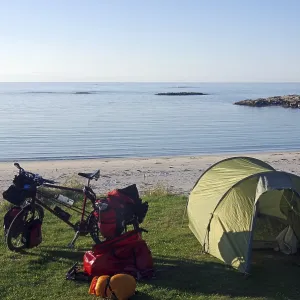 Campsite on the beach with a tent and cycling equipment in peaceful surroundings Campsite on the beach with a tent and cycling equipment in peaceful surroundings
