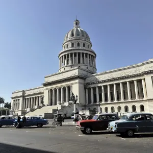 The Capitol surrounded by vintage and modern cars on the street on a sunny day The Capitol surrounded by vintage and modern cars on the street on a sunny day