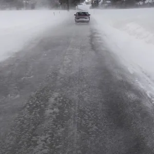 Car driving away in winter blizzard on a narrow snowy road in Norway Car driving away in winter blizzard on a narrow snowy road in Norway