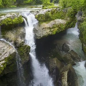 Cascading water through green, rocky gorge in lush nature Cascading water through green, rocky gorge in lush nature