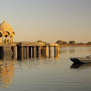 Cenotaph called chhatri and pillars reflection and rowing boat in waters of Gadsisar or Gadisar lake