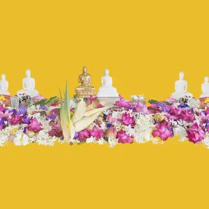 Ceremonial flowers and buddha figurines isolated on yellow background
