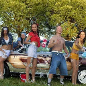 Cheerful young female friends in casual clothes standing near vintage car and looking at camera Cheerful young female friends in casual clothes standing near vintage car and looking at camera