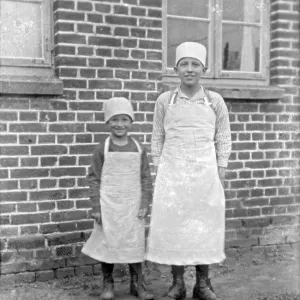 Children of a baker family pose with aprons and headgear for the photo Children of a baker family pose with aprons and headgear for the photo