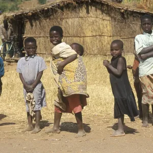 Children in front of a straw hut on the side of the road Children in front of a straw hut on the side of the road