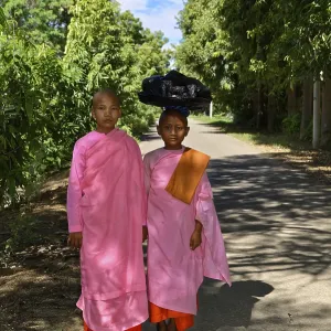 Two children in traditional pink clothes on a sunlit forest path