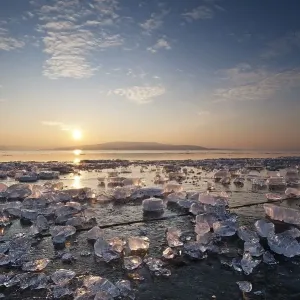 Chunks of ice lying on icy surface on the shore of Reichenau Island at sunset Chunks of ice lying on icy surface on the shore of Reichenau Island at sunset