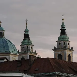 Three church towers and a dome rise against a cloudy evening sky