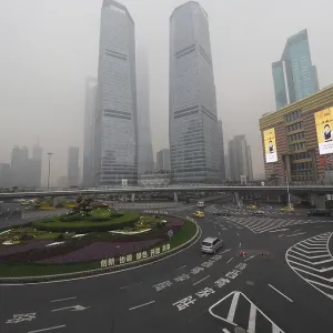 City scene with roundabout and skyscrapers in fog under grey sky