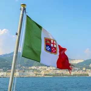 Civil ensign of Italy. National Flag on the background of the sea and mountains