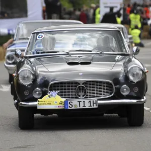 A classic blue Lancia drives on the road in a classic car race A classic blue Lancia drives on the road in a classic car race