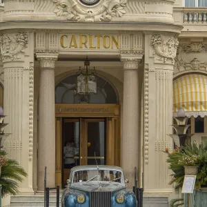 A classic car parked in front of the entrance of an elegant historic hotel