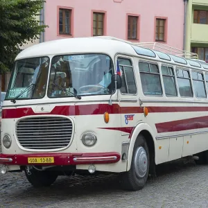 A classic old bus on a cobbled street in a town with colourful buildings