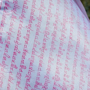 Close up of buddhist prayers on the white praying flag Close up of buddhist prayers on the white praying flag