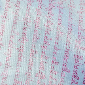 Close up of buddhist prayers on the white praying flag Close up of buddhist prayers on the white praying flag