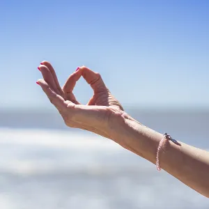 Nahaufnahme einer mittleren erwachsenen Frau, die mit ihrer Hand den Gyan Mudra ausführt am Strand. Nahaufnahme einer mittleren erwachsenen Frau, die mit ihrer Hand den Gyan Mudra ausführt am Strand.