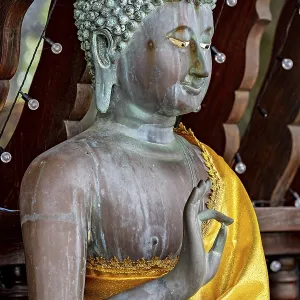 Close-up of a Buddha statue in bronze with a bright yellow cloth Close-up of a Buddha statue in bronze with a bright yellow cloth