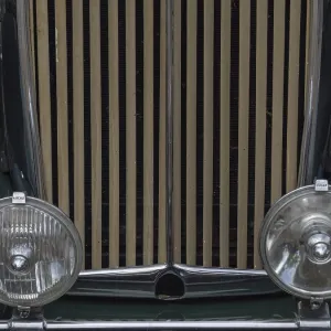 Close-up of a green vintage car with vertical radiator grille and round headlights