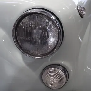 Close-up of a light blue vintage car with distinctive headlights and chrome