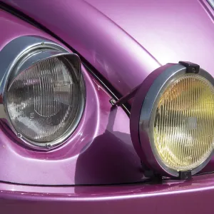 Close-up of the front of a pink classic car with characteristic twin headlights Close-up of the front of a pink classic car with characteristic twin headlights