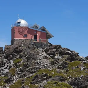 Close-up of a red observatory on a rocky hill under a blue sky Close-up of a red observatory on a rocky hill under a blue sky