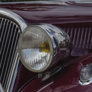 Close-up of a red vintage car with round chrome headlights