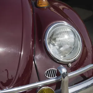 Close-up of a red vintage car with shiny headlight and bumper Close-up of a red vintage car with shiny headlight and bumper