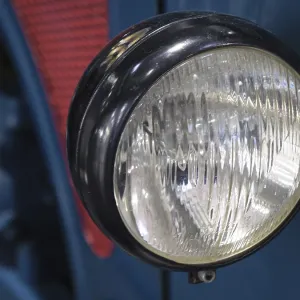 Close-up of a round headlight of a blue vintage car