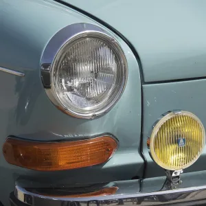 Close-up of the front of a turquoise classic car with orange and yellow headlights Close-up of the front of a turquoise classic car with orange and yellow headlights