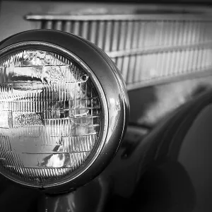Close-up of a vintage car headlight and grille in black and white in St