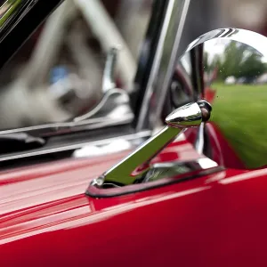 Nahaufnahme eines alten Autos-Seitenrückspiegels in Chrom mit einem roten Leib in St.
