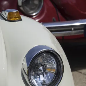 Close-up of a white vintage car with red car in the background Close-up of a white vintage car with red car in the background