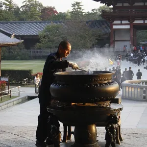 Closing time: an attendant clears away incense sticks at Todaiji temple in Nara city