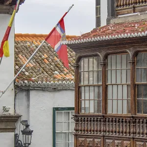 Detail of a colonial building with wooden balcony and waving flags