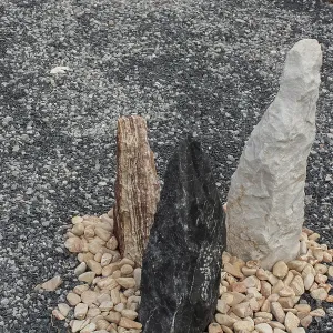 Three colorful standing stones arranged in a circle of pebbles on a grey gravel background Three colorful standing stones arranged in a circle of pebbles on a grey gravel background