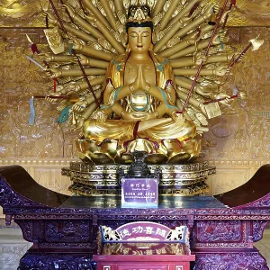 Complex golden Buddha statue with numerous arms in an ornate room Complex golden Buddha statue with numerous arms in an ornate room