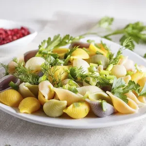 Conchiglie colored pasta with fresh greengrocery on a linen tablecloth on white wooden background Conchiglie colored pasta with fresh greengrocery on a linen tablecloth on white wooden background