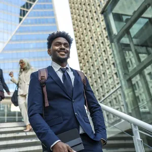Confident black businessman walking down modern city stairs
