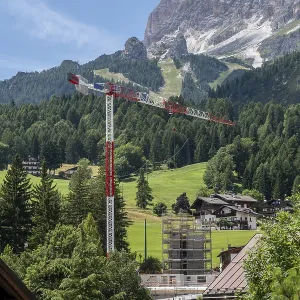 Construction crane in front of a mountain backdrop in Cortina