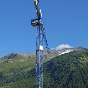 Construction Crane and swiss Alps with Blue Clear Sky and Sunlight in Andermatt