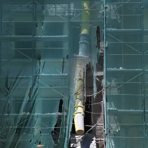 Construction site, house with scaffolding and a net in front of it as dust protection