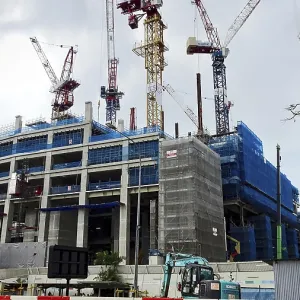 Construction site of a large building with several cranes under overcast sky Construction site of a large building with several cranes under overcast sky