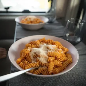 Cooked fusilli with tomato sauce and parmesan cheese on the table in the campervan